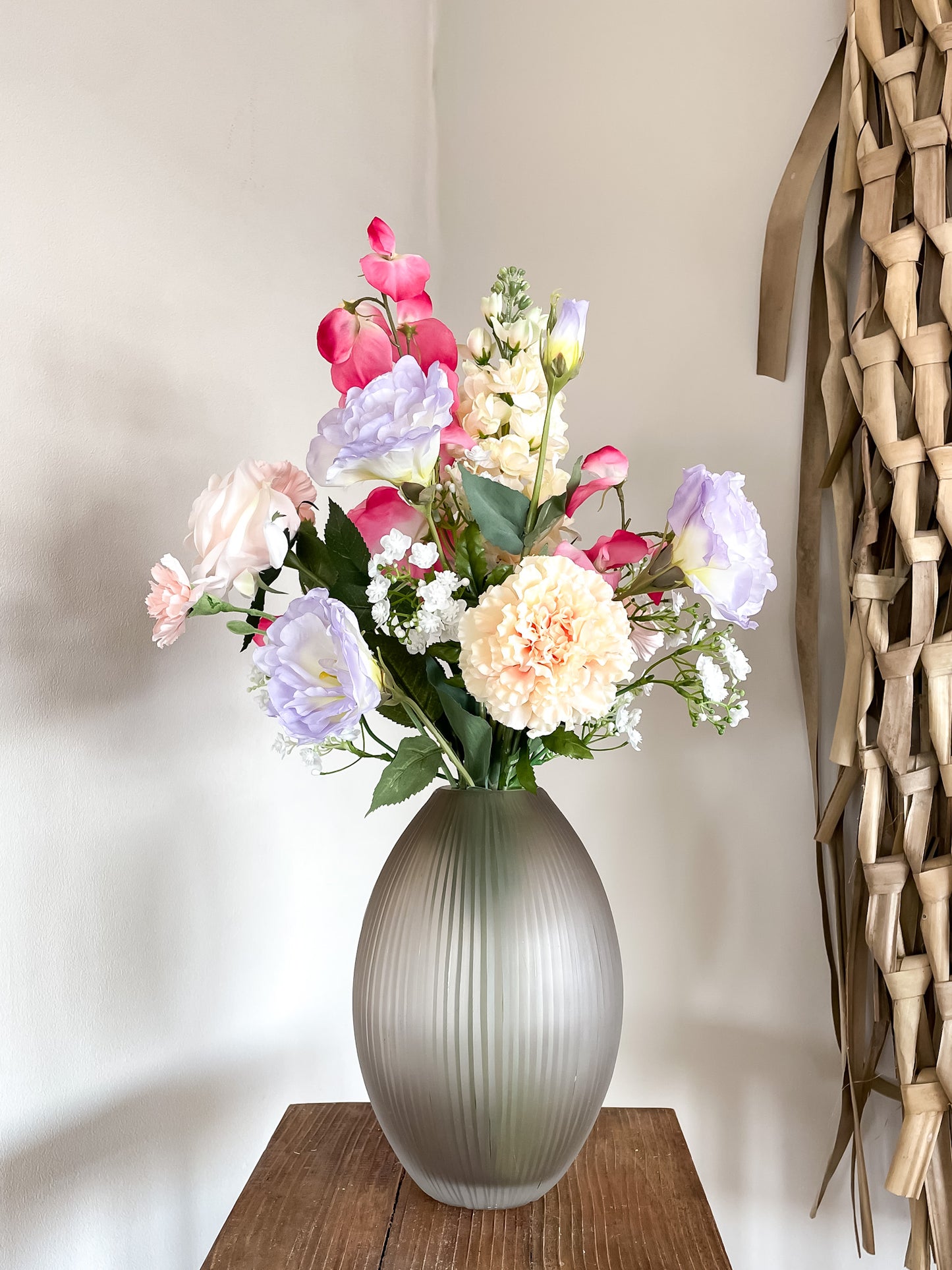 Vaas met smalle opening in mat bruin gecombineerd met kleurrijk zijden boeket met kunstbloemen.