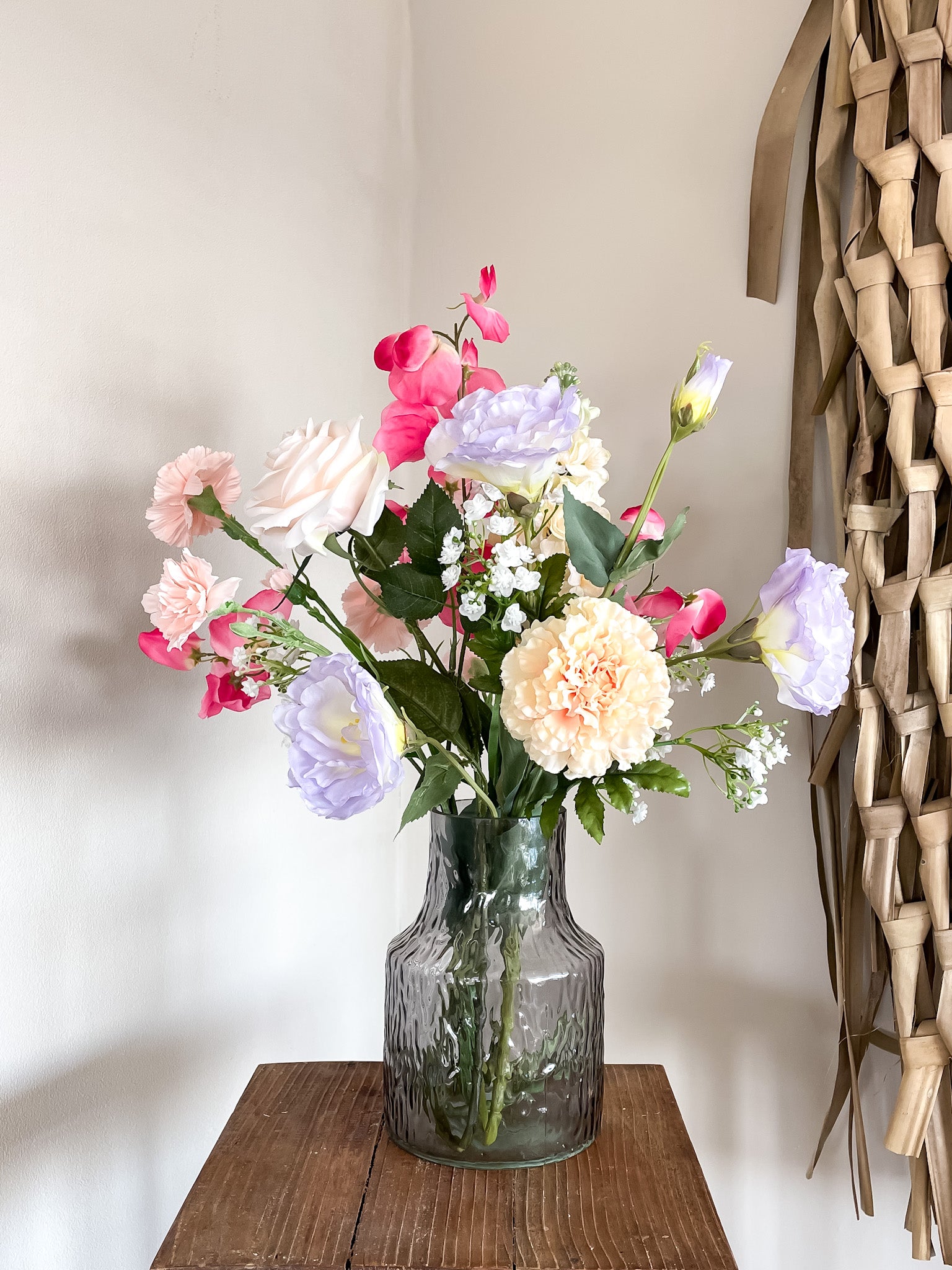 Kunstbloemen in zachte tinten, prachtig geschikt in een luxe vaasje voor een sfeervolle look.