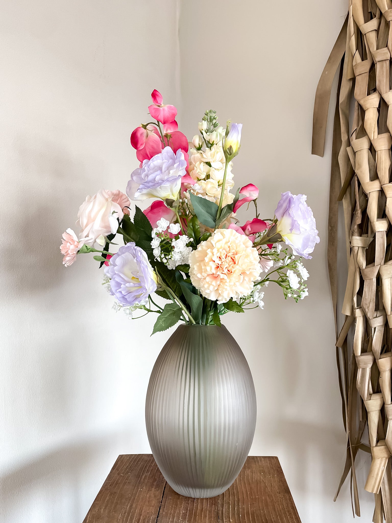 Vaas met smalle opening in mat bruin gecombineerd met kleurrijk zijden boeket met kunstbloemen.