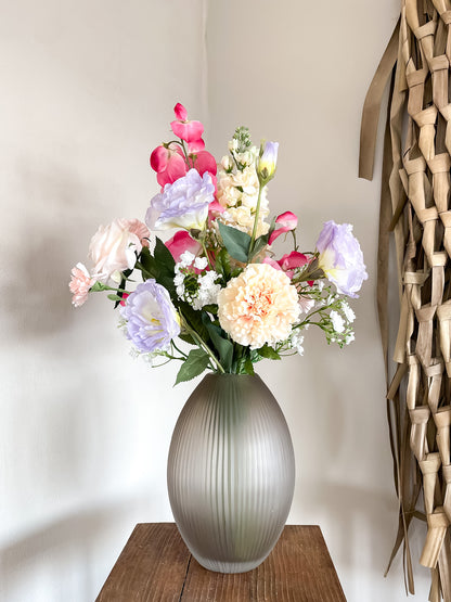 Vaas met smalle opening in mat bruin gecombineerd met kleurrijk zijden boeket met kunstbloemen.