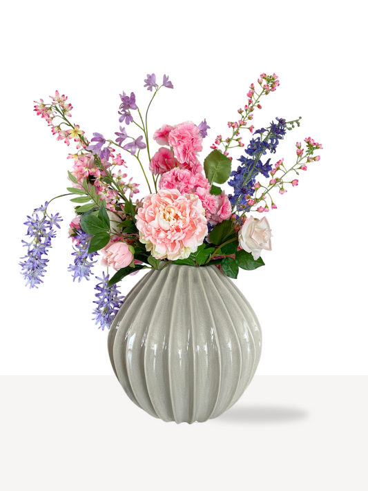 Stijlvol zijden kunstbloemen boeket met romantische lila en pastelroze bloemen in een moderne zandkleurige vaas. Perfect als luxe interieurdecoratie en duurzaam alternatief voor verse bloemen.