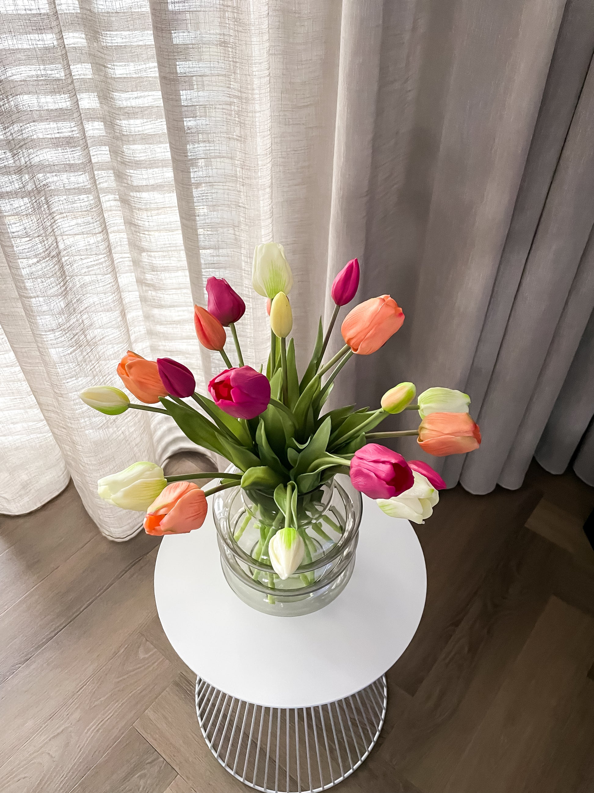 Glazen bubble vaas met nep tulpen in paars, zalm en wit.