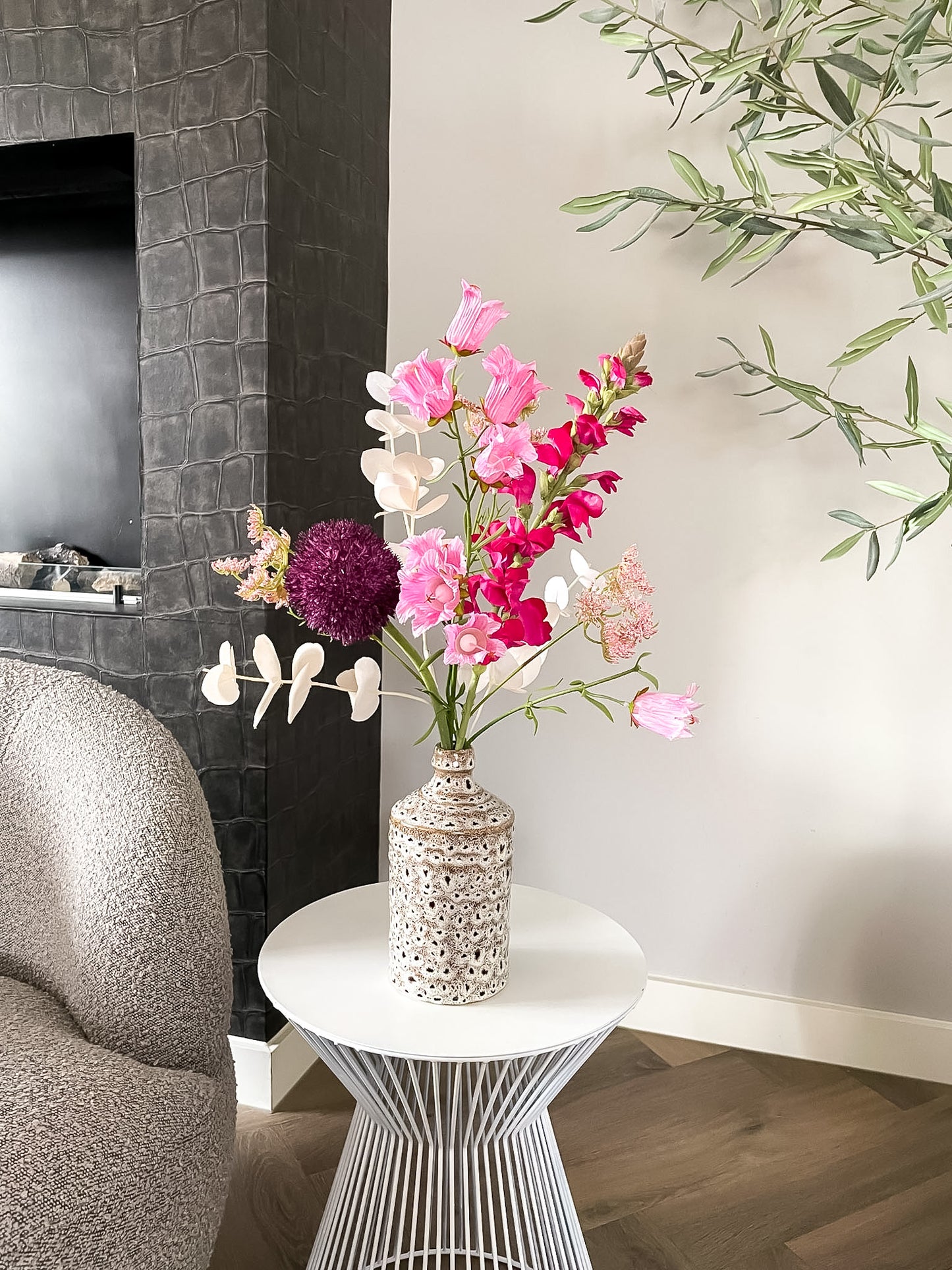 Luxe roze zijden bloemenboeket in keramieken vaas op witte bijzettafel in modern interieur