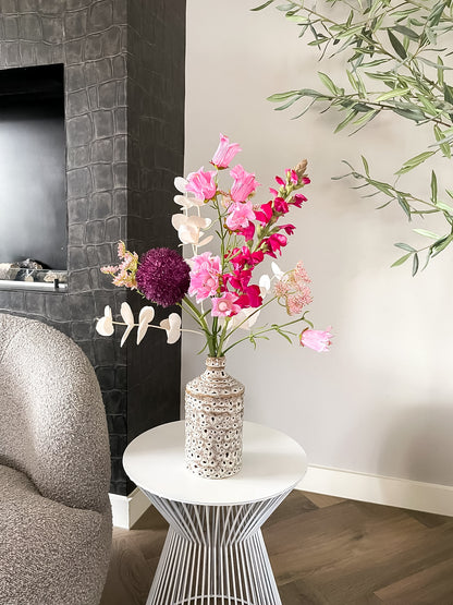 Luxe roze zijden bloemenboeket in keramieken vaas op witte bijzettafel in modern interieur