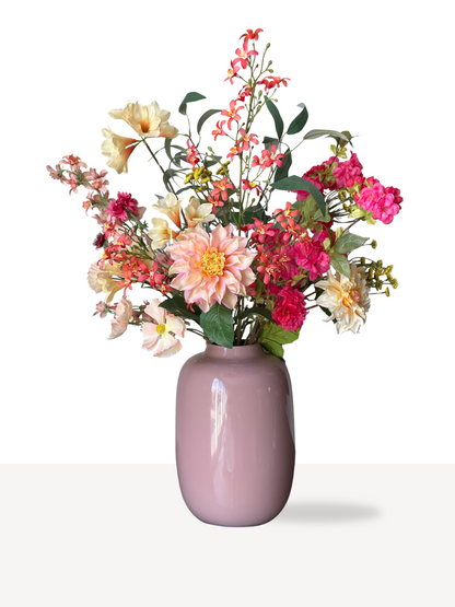 Een mooi kleurrijk boeket gecombineerd in een mooi glanzende roze vaas.