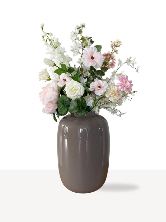 Prachtig luxe zijden boeket met witte en zachtroze bloemen in een stijlvolle taupekleurige vaas.