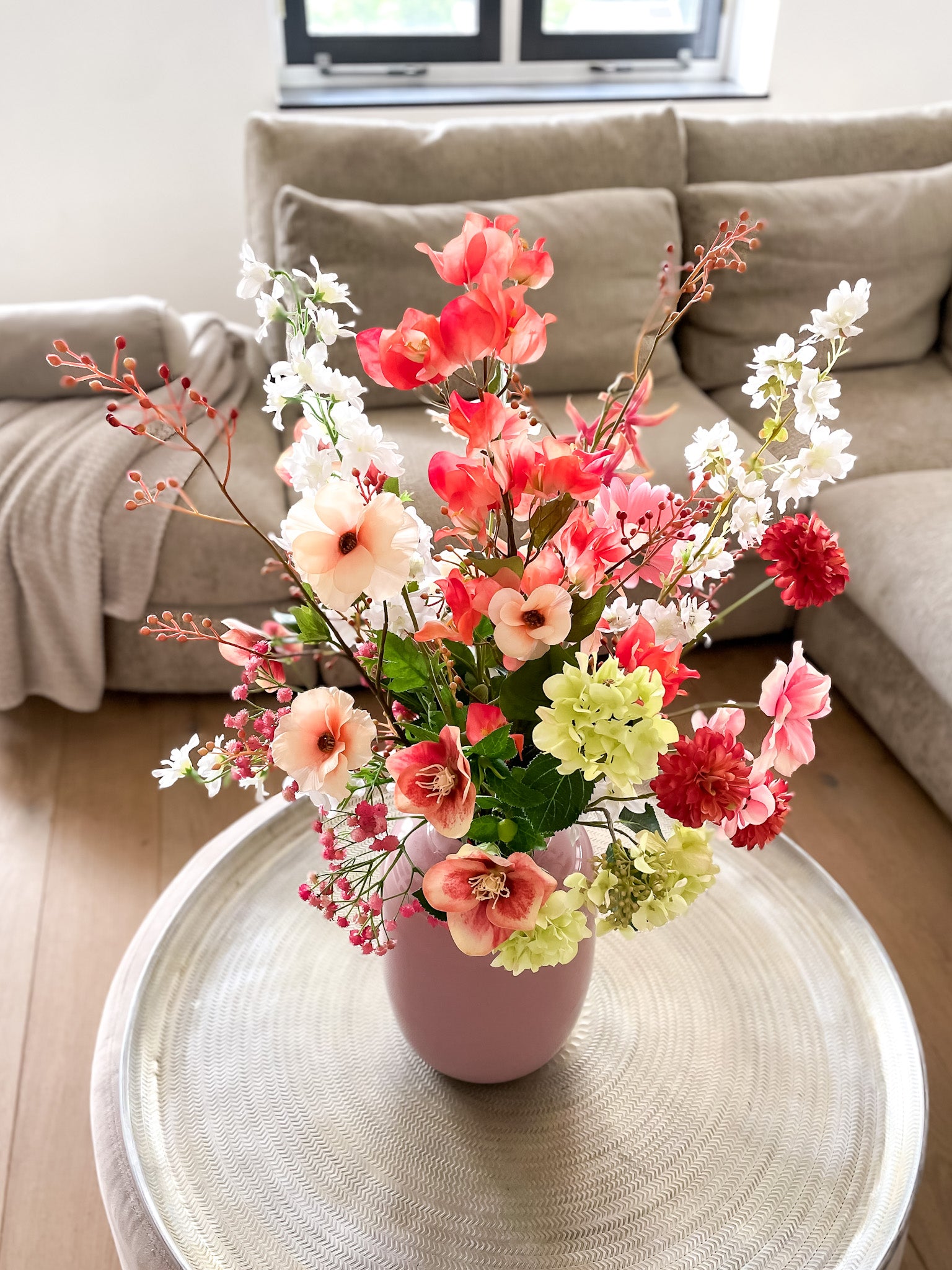 Zijden boeket in roze glazen vaas met bloemen in roze, oranje en groen