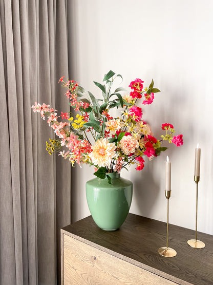 Luxe zijden boeket met oranje, roze en perzikkleurige bloemen in groene glanzende vaas