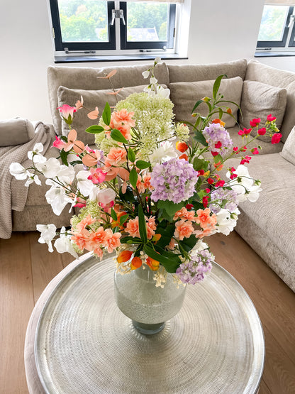 Vrolijk kunstbloemen boeket in felroze, oranje, paars en groen, gepresenteerd in groene vaas.