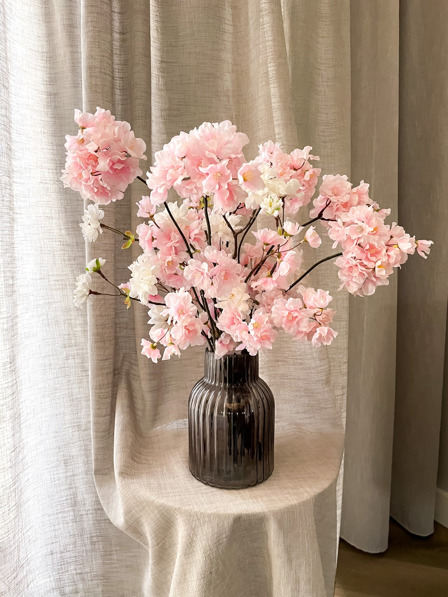 wit roze zijden bloesems in ribbel zwart transparante vaas