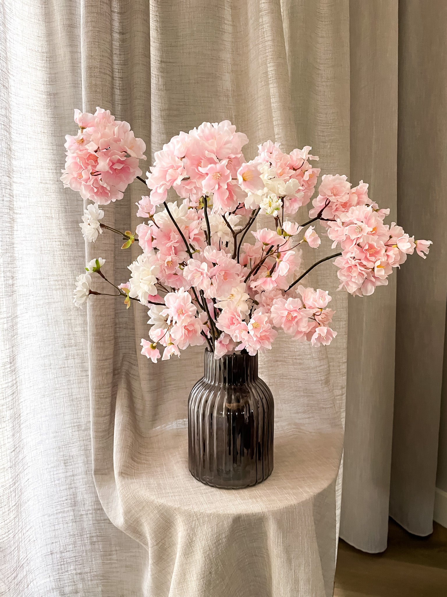 wit roze zijden bloesems in ribbel zwart transparante vaas