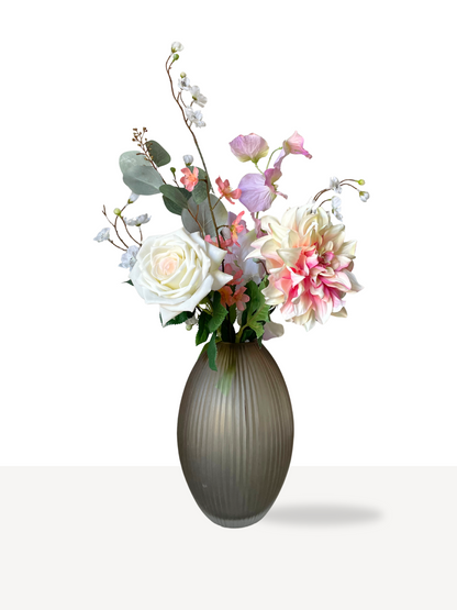 Zacht zijden boeket met witte, roze en lila bloemen in een elegante grijze vaas.